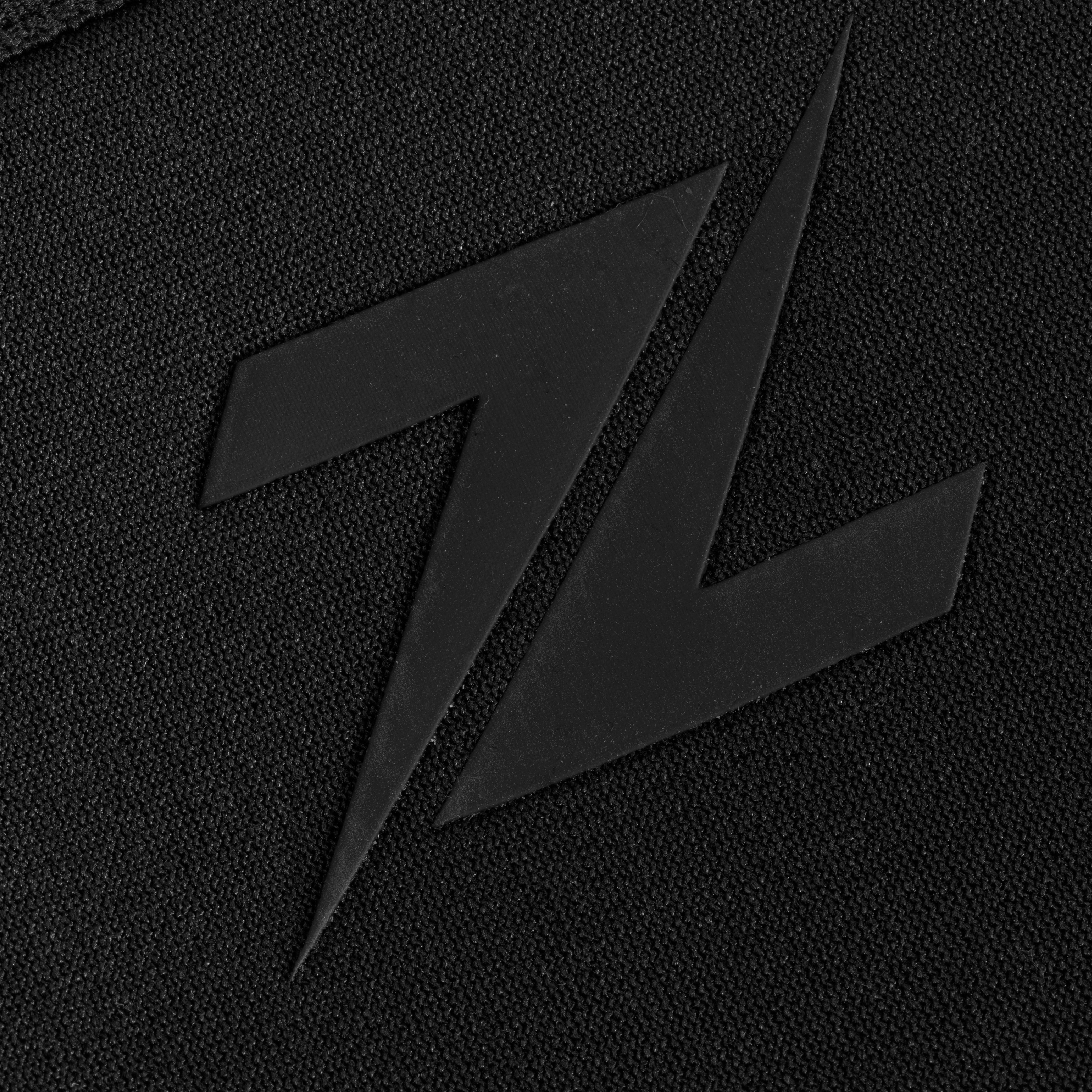 Close-up van het ZEUZ logo op de geheel zwarte knee sleeves – premium afwerking voor sporters