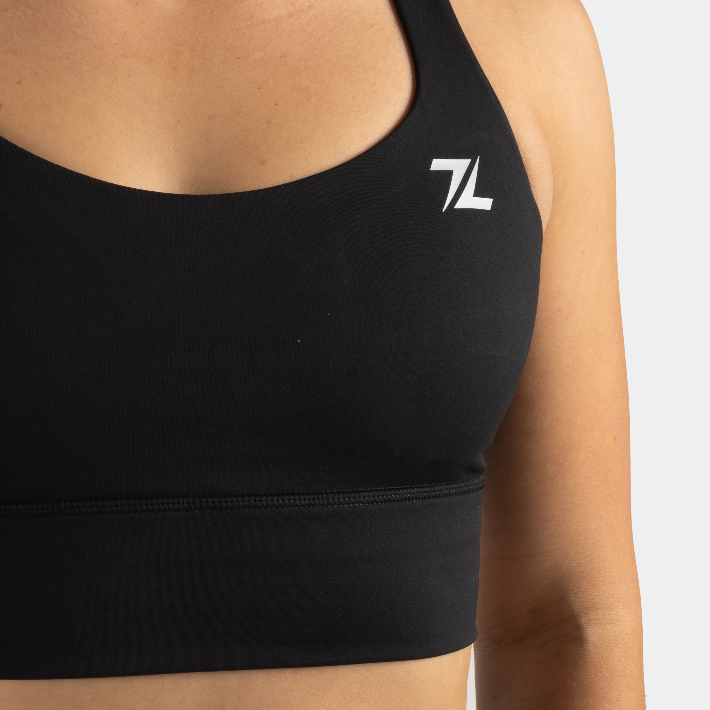 Detail van het logo aan de voorkant van de ZEUZ Sportbeha zwart